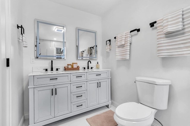 full bath featuring toilet, baseboards, and double vanity