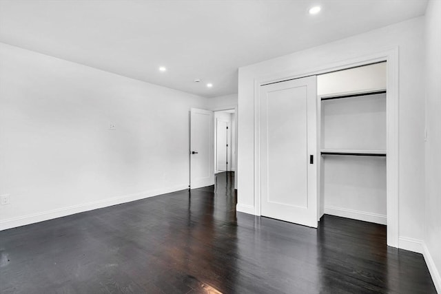 unfurnished bedroom featuring baseboards, dark wood finished floors, recessed lighting, and a closet
