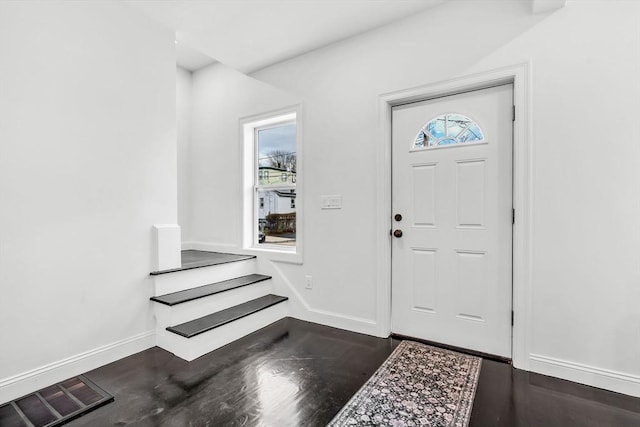 foyer entrance featuring wood finished floors, baseboards, and stairway