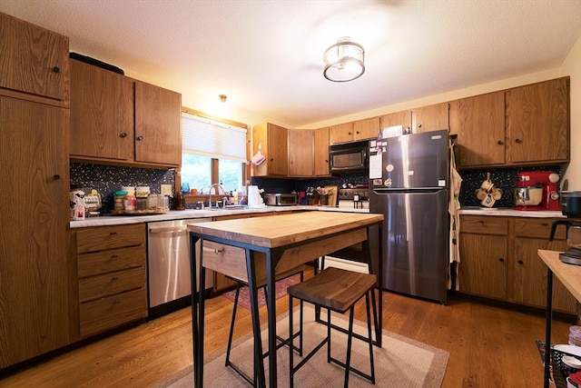 19 Hadley St Unit 14, South Hadley, MA 01075 - kitchen with appliances with stainless steel finishes, tasteful backsplash, wood finished floors, and brown cabinets