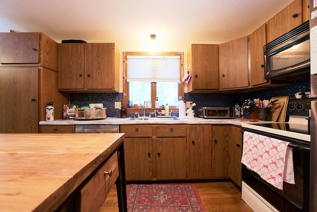 19 Hadley St Unit 14, South Hadley, MA 01075 - kitchen featuring range with electric cooktop, black microwave, brown cabinetry, light wood-style floors, and tasteful backsplash