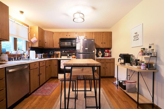 19 Hadley St Unit 14, South Hadley, MA 01075 - kitchen featuring appliances with stainless steel finishes, wood finished floors, a sink, tasteful backsplash, and light countertops