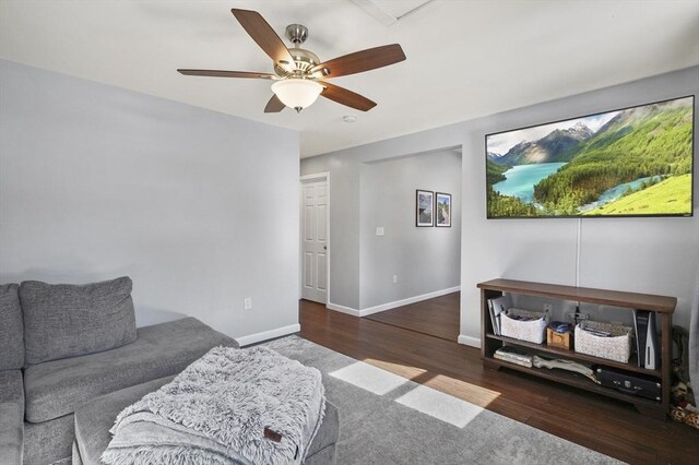 living area with a ceiling fan, wood finished floors, and baseboards