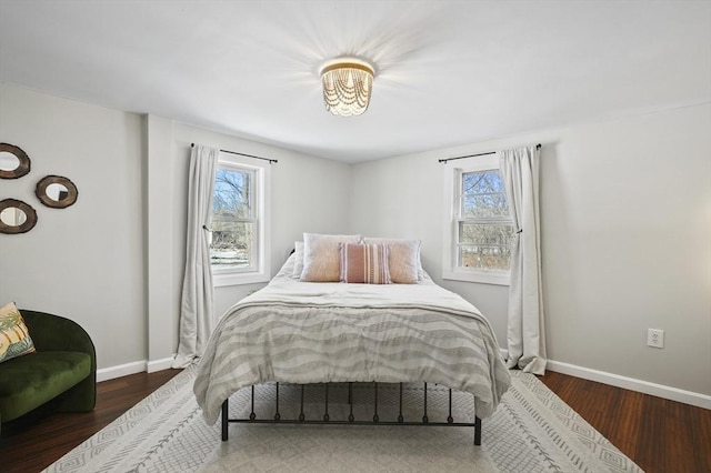 bedroom featuring baseboards, multiple windows, and wood finished floors