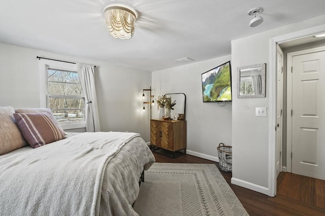 bedroom featuring visible vents, baseboards, and wood finished floors