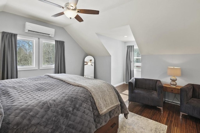 bedroom featuring vaulted ceiling, multiple windows, an AC wall unit, and wood finished floors