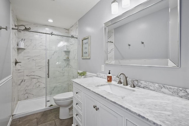 bathroom featuring a marble finish shower, toilet, and vanity