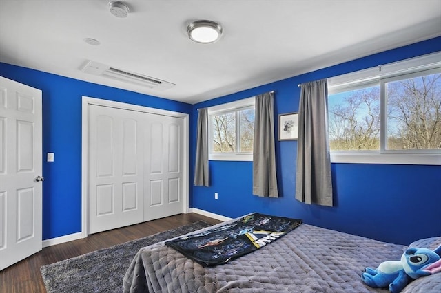 bedroom featuring a closet, visible vents, baseboards, and wood finished floors