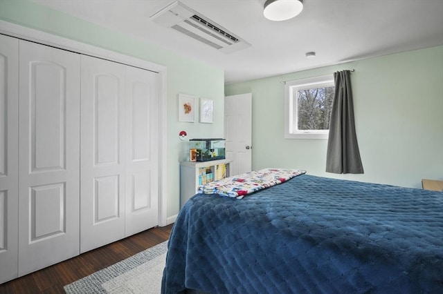 bedroom with wood finished floors, visible vents, and a closet