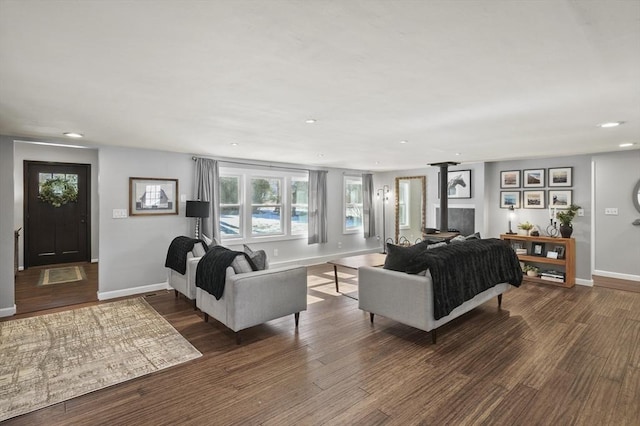 living area with a wood stove, recessed lighting, wood finished floors, and baseboards