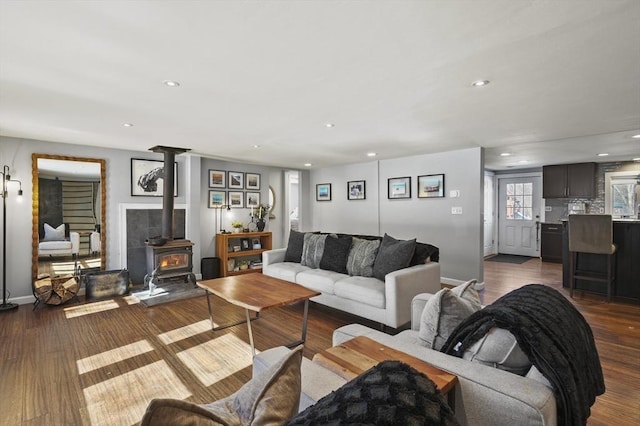 living area with recessed lighting, baseboards, dark wood-type flooring, and a wood stove