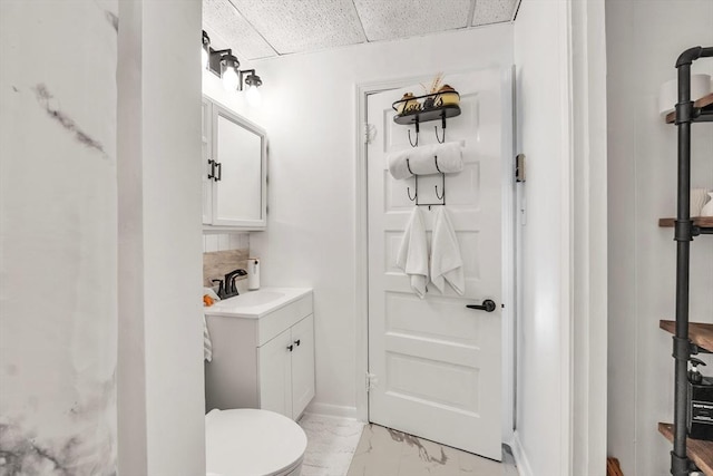 bathroom featuring tasteful backsplash, a drop ceiling, vanity, and toilet