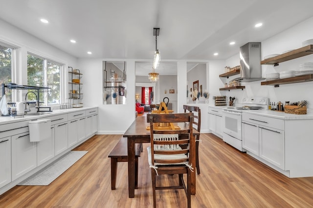 kitchen with extractor fan, white range with electric stovetop, light hardwood / wood-style flooring, white cabinetry, and hanging light fixtures