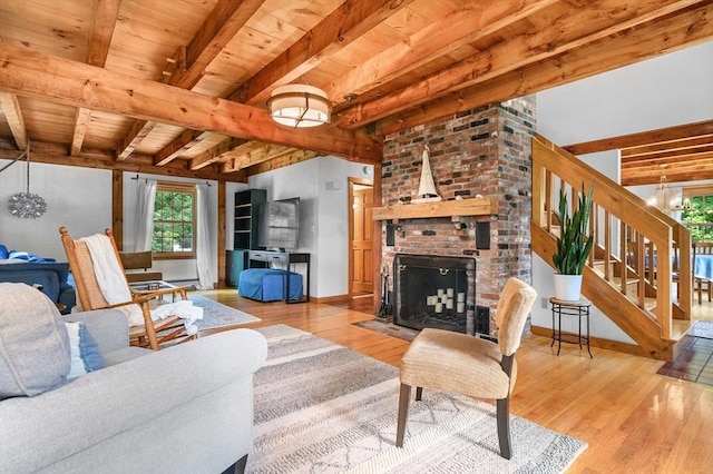 living area with a brick fireplace, wood ceiling, stairs, and wood finished floors