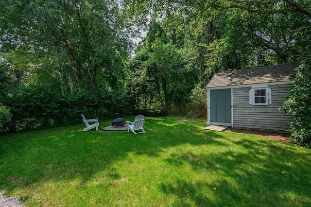 view of yard featuring an outdoor structure, a fire pit, and a shed