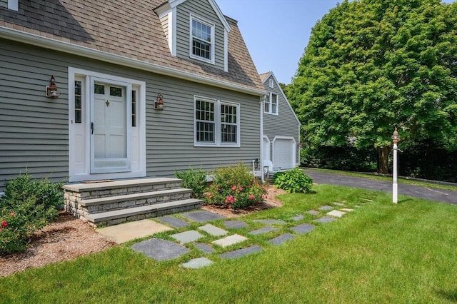 view of front of house featuring a garage, driveway, a shingled roof, and a front lawn