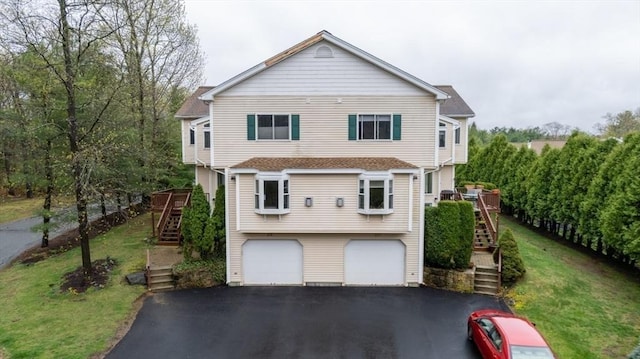 view of front facade featuring a garage, a front lawn, stairs, and aphalt driveway
