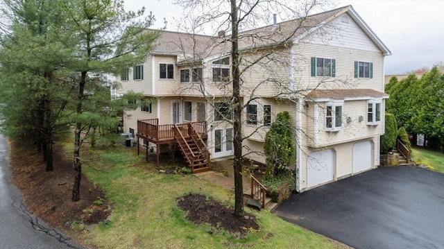 view of front of house featuring a wooden deck, an attached garage, stairway, and aphalt driveway