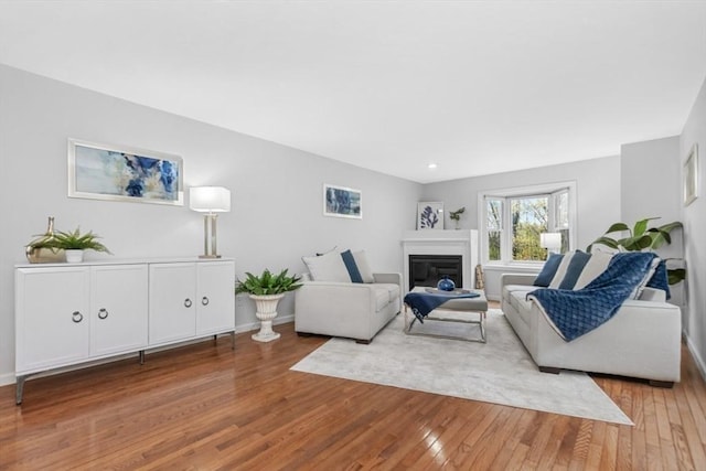 living area featuring baseboards, recessed lighting, a glass covered fireplace, and wood finished floors