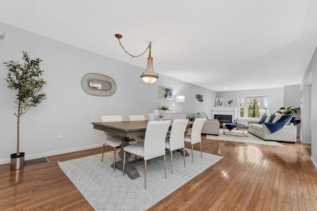 dining space with baseboards, a fireplace, and hardwood / wood-style flooring