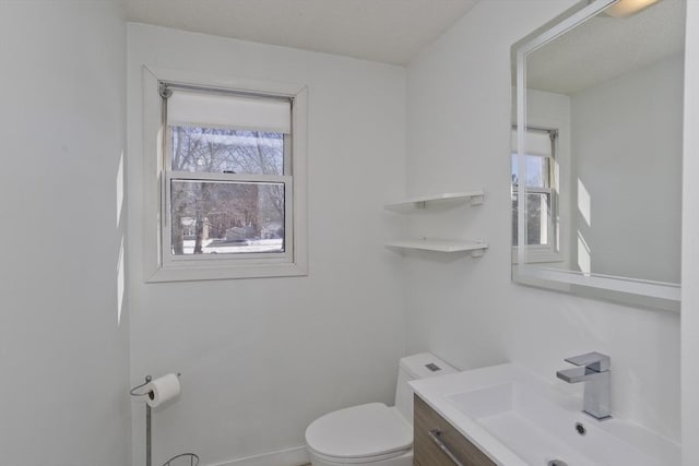 bathroom with vanity, toilet, and baseboards