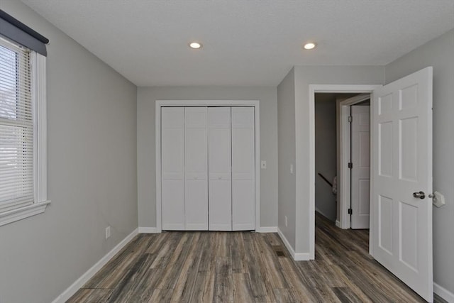 unfurnished bedroom with dark wood finished floors, recessed lighting, baseboards, and a closet