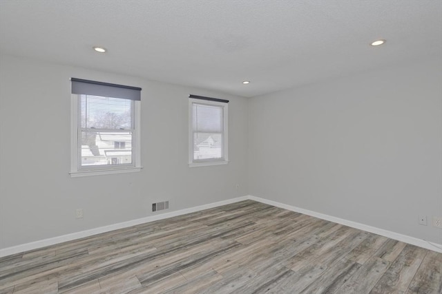 spare room featuring visible vents, baseboards, and wood finished floors