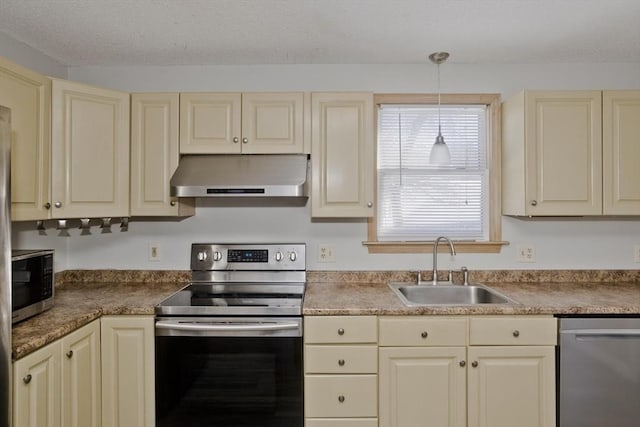 kitchen with appliances with stainless steel finishes, cream cabinets, extractor fan, and a sink