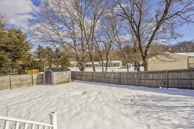 yard covered in snow featuring a fenced backyard, an outbuilding, and a storage shed