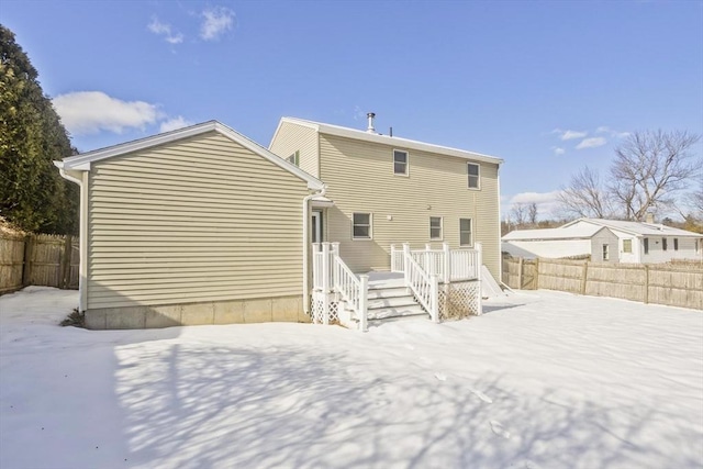 snow covered rear of property featuring a deck and fence