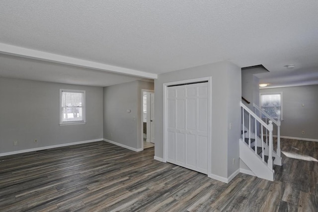 foyer entrance featuring dark wood-style floors, a textured ceiling, stairs, and baseboards