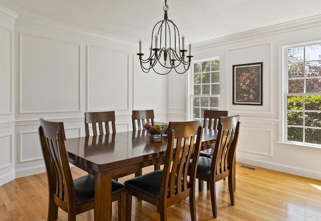 dining room with light wood-style floors, a chandelier, visible vents, and a decorative wall