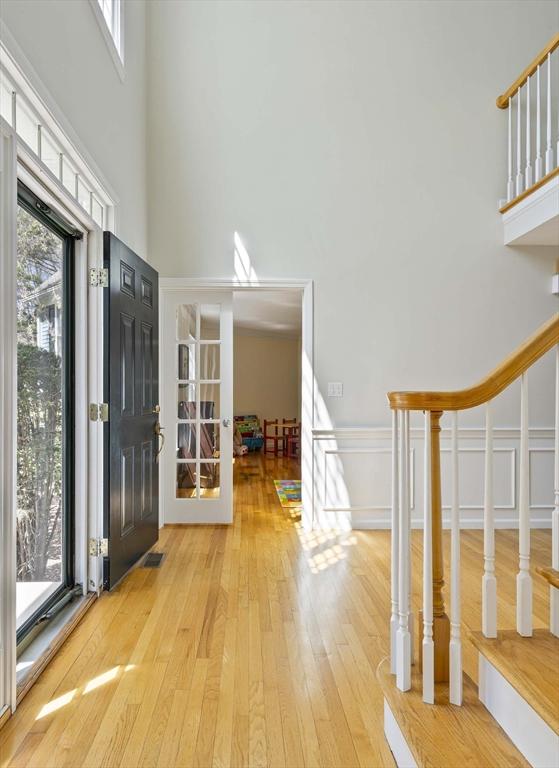 entryway featuring visible vents, a high ceiling, a healthy amount of sunlight, and hardwood / wood-style flooring