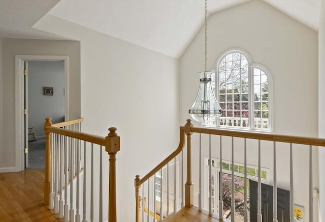 stairway with wood finished floors, a chandelier, and high vaulted ceiling