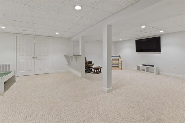 finished basement featuring baseboards, carpet, a drop ceiling, and visible vents