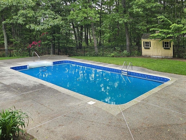 view of swimming pool with fence, a fenced in pool, an outbuilding, a patio, and a yard