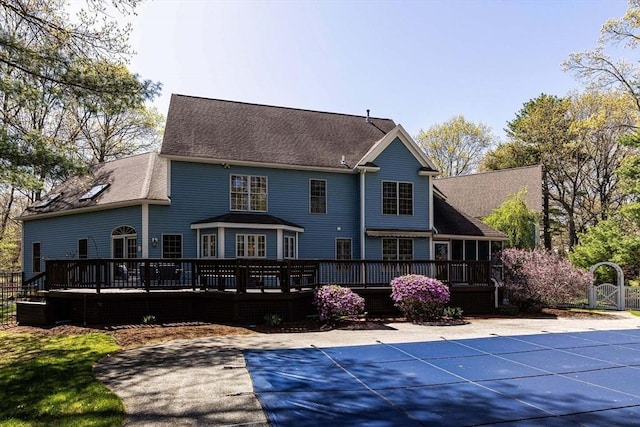 rear view of house featuring a fenced in pool, a shingled roof, a patio area, and a wooden deck