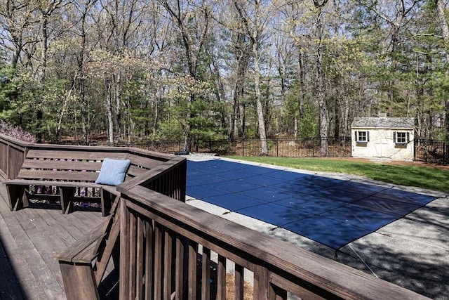 view of pool featuring a deck, an outbuilding, fence, a fenced in pool, and a storage unit