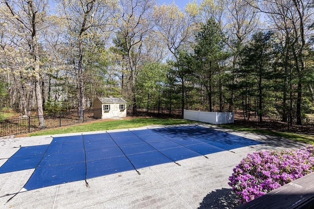 view of swimming pool featuring a fenced in pool, a fenced backyard, a shed, and an outbuilding