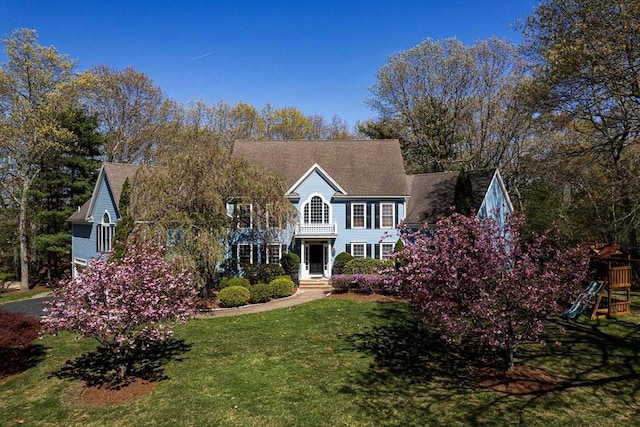 colonial inspired home featuring a playground and a front lawn
