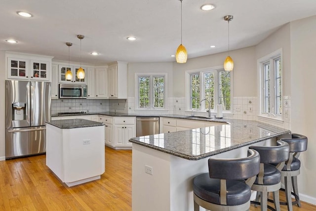 kitchen with a sink, light wood-style flooring, a peninsula, and stainless steel appliances