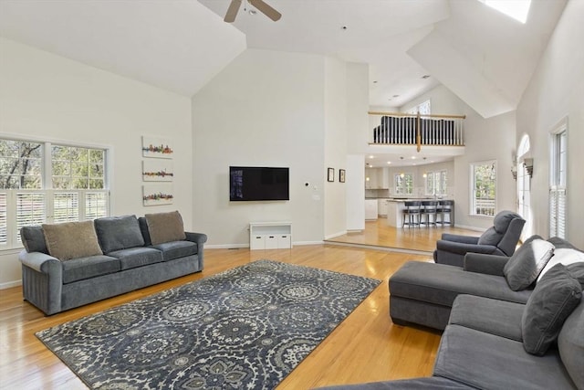 living room with plenty of natural light, ceiling fan, wood finished floors, and high vaulted ceiling
