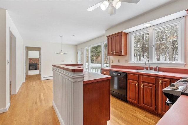 kitchen with sink, hanging light fixtures, light wood-type flooring, black dishwasher, and a baseboard heating unit