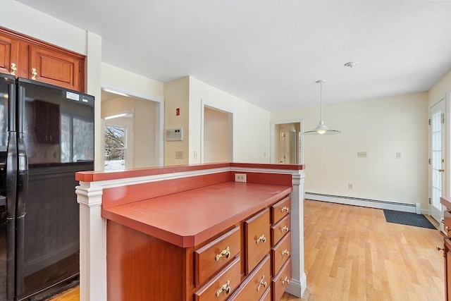 kitchen featuring hanging light fixtures, a baseboard radiator, black refrigerator, and light hardwood / wood-style floors