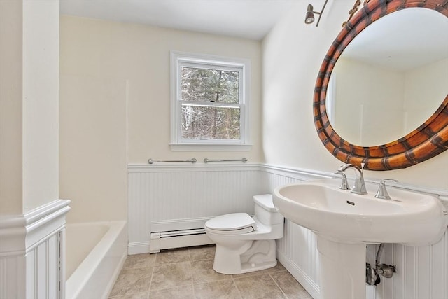 bathroom with tile patterned floors, toilet, a bathtub, and a baseboard heating unit