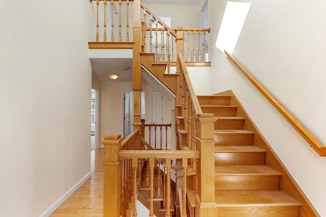 stairway featuring a towering ceiling and hardwood / wood-style floors