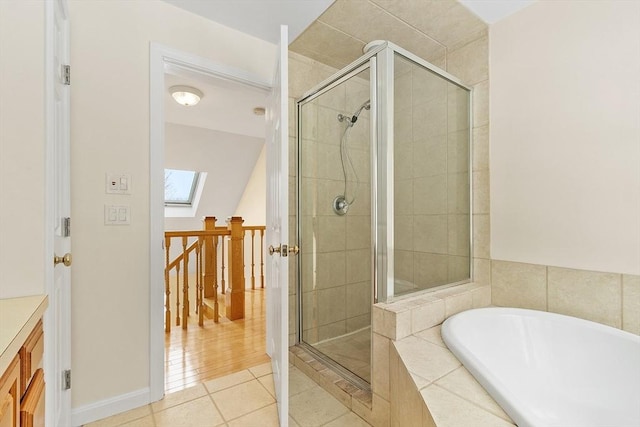 bathroom featuring tile patterned flooring, shower with separate bathtub, and a skylight