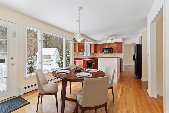 dining room featuring plenty of natural light, light hardwood / wood-style floors, and a baseboard heating unit