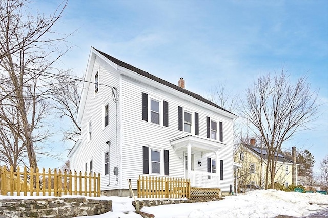 view of front facade featuring a chimney and fence