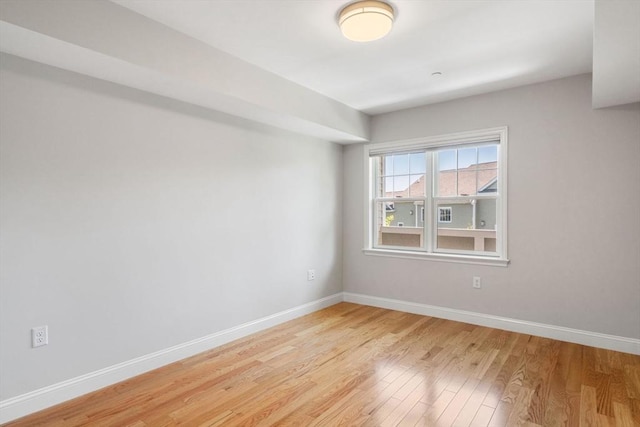 spare room with baseboards and light wood finished floors